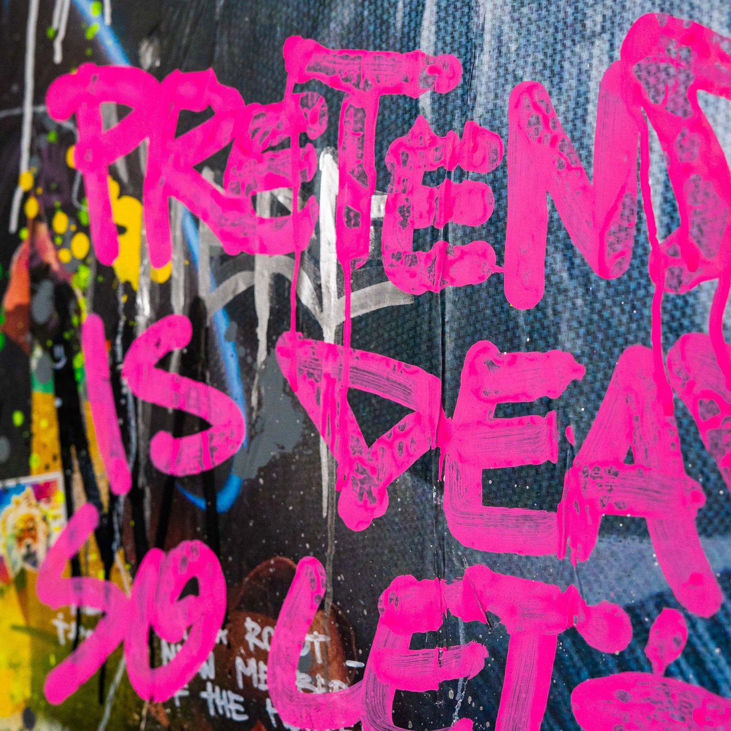 Pink spray-painted text on a textured surface with colorful background