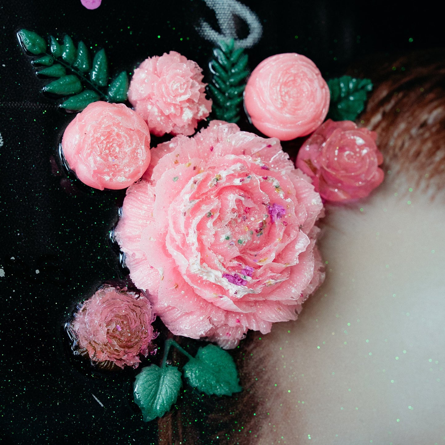 Decorative pink flowers with green leaves on a black background