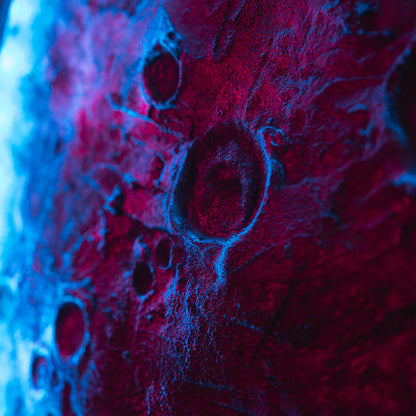 Close-up of textured surface with circular patterns under blue and red lighting