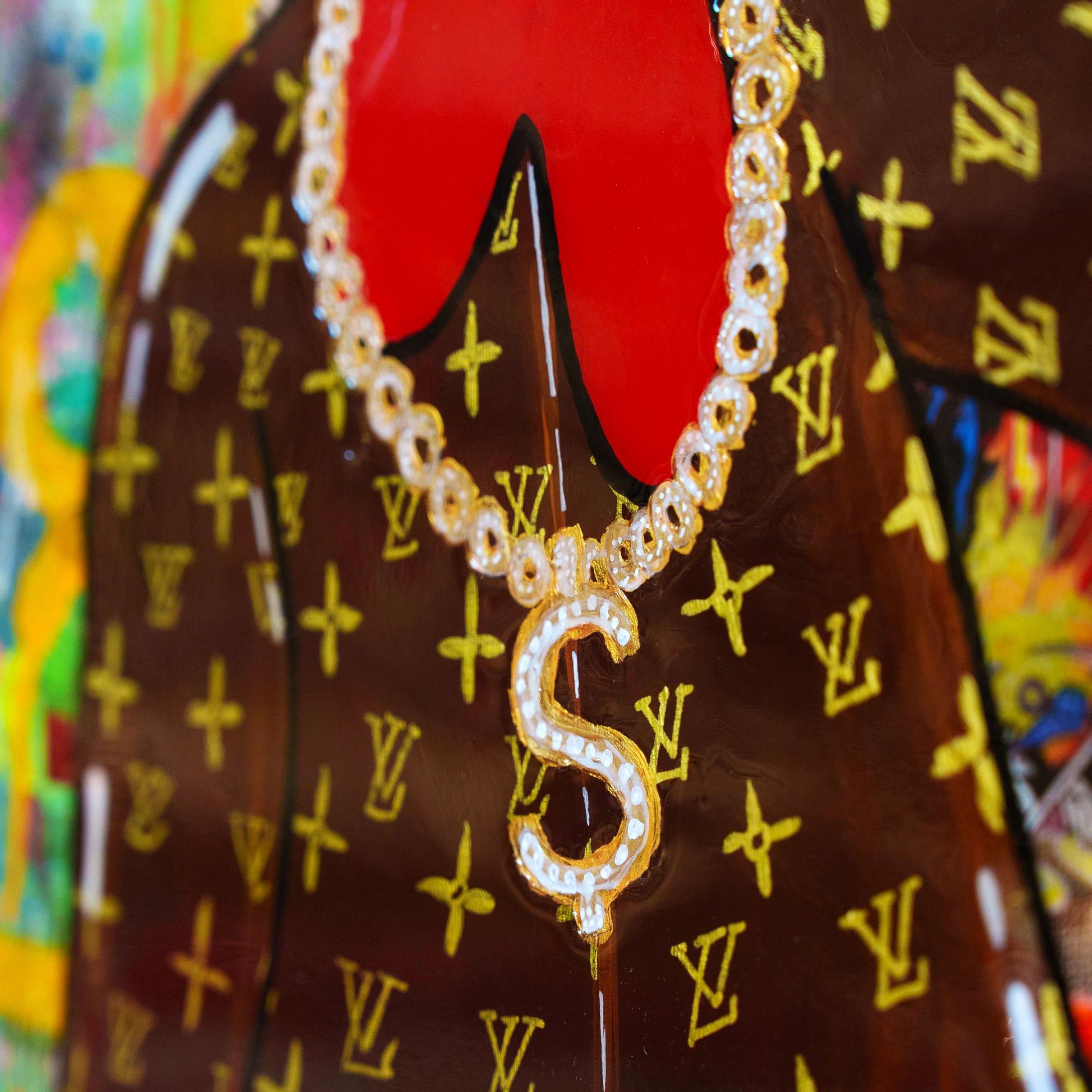 Gold necklace with a letter 'S' pendant on a brown background with yellow logos.