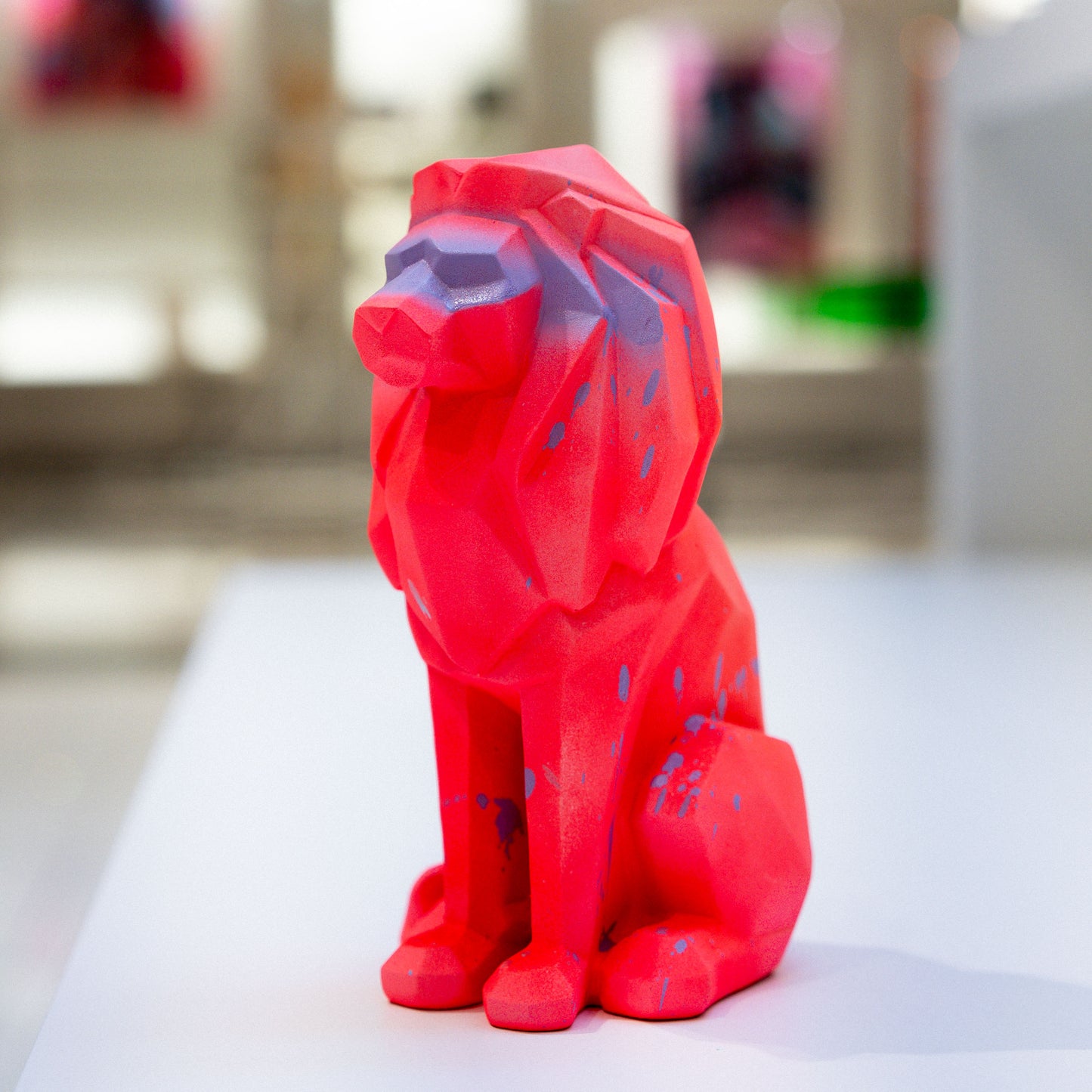 Red geometric dog sculpture on a white surface with a blurred background