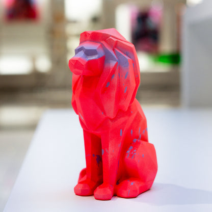 Red geometric dog sculpture on a white surface with a blurred background