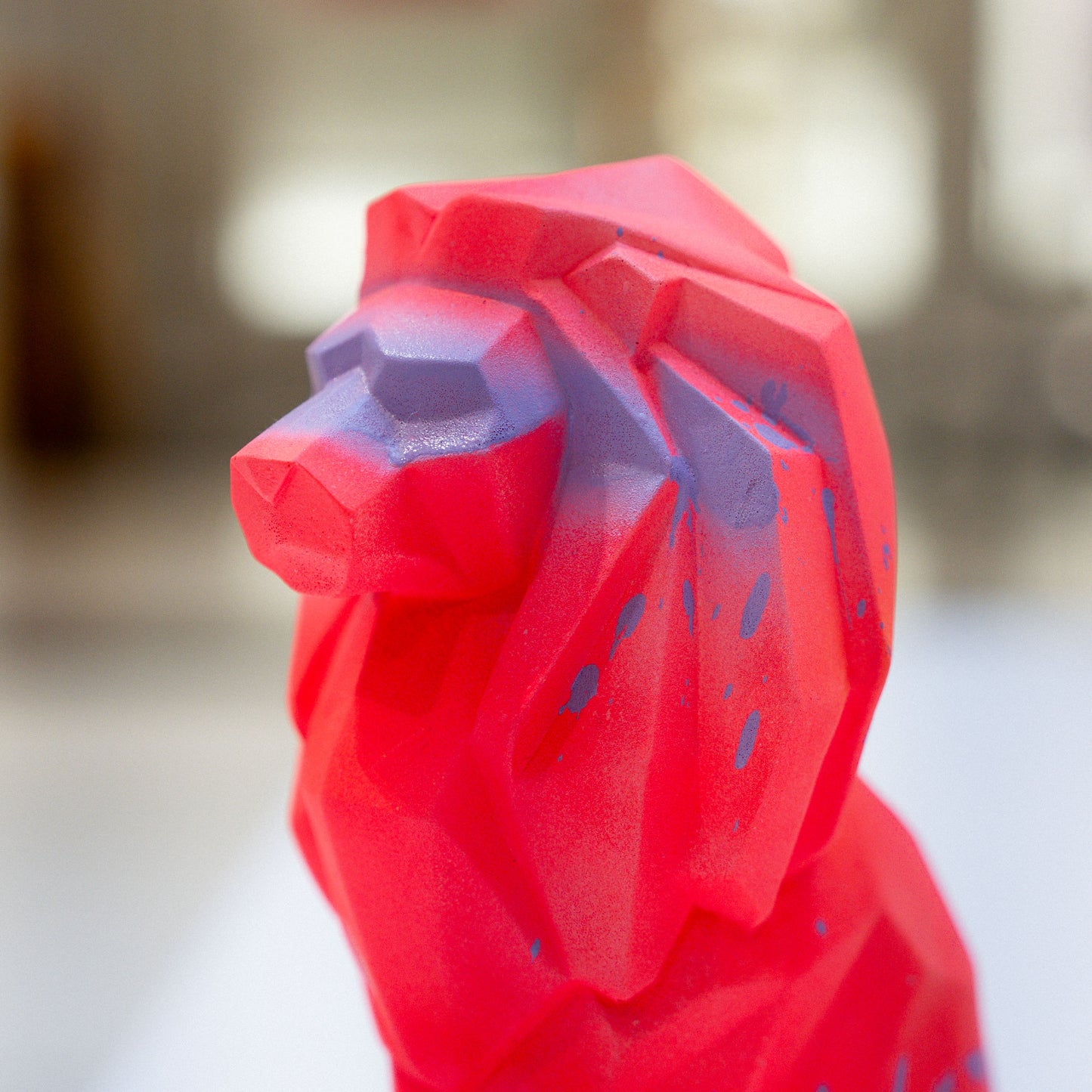 Red geometric rooster sculpture on a blurred background