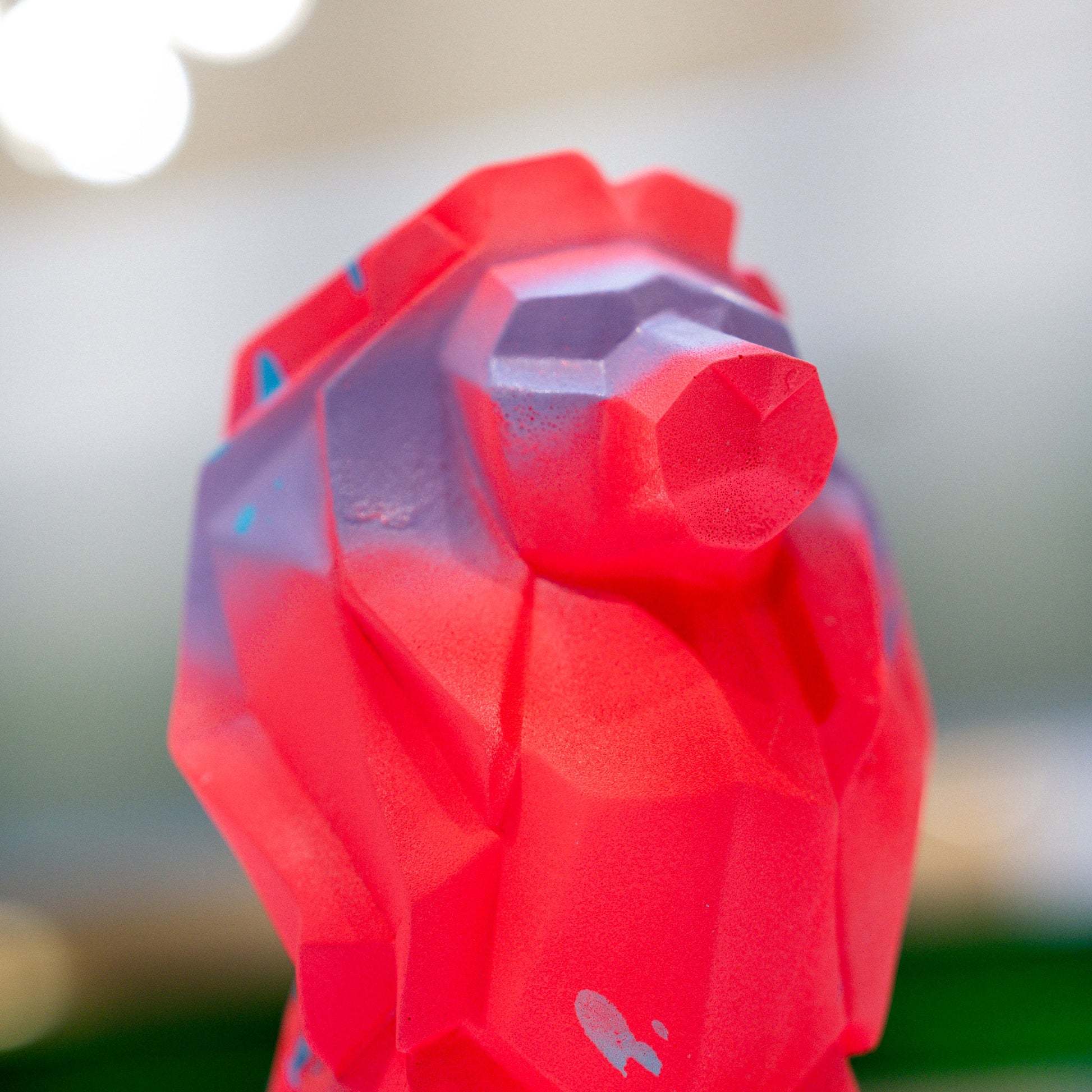 Close-up of a red and purple geometric-patterned bottle cap with a blurred background.