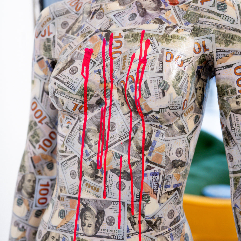 Mannequin covered with dollar bill pattern and red paint streaks