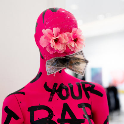 Person wearing a bright pink outfit with flowers and money, with text on a blurred background