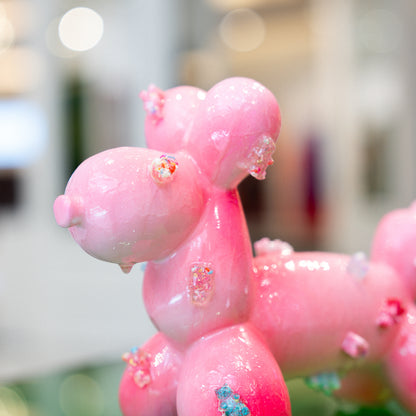 Pink balloon dog sculpture with decorative elements on a blurred background