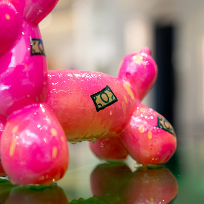 Pink balloon dog sculpture with 'LOL' branding on a reflective surface.