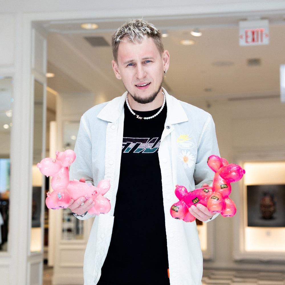 Person holding pink balloon animals in a mall setting