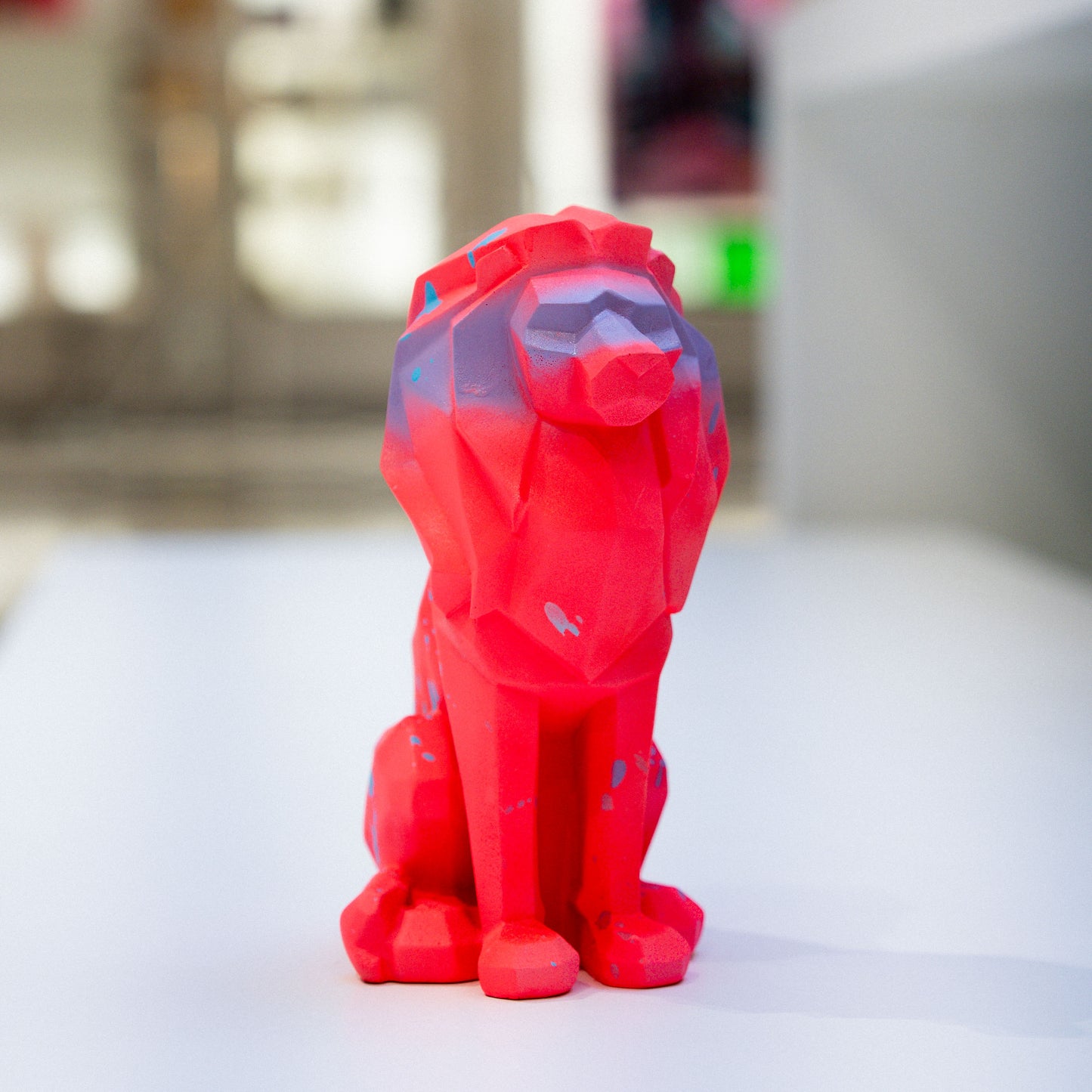 Red lion-shaped object on a white surface with a blurred background