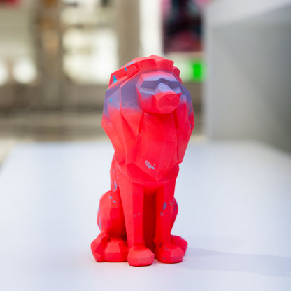 Red lion-shaped object on a white surface with a blurred background